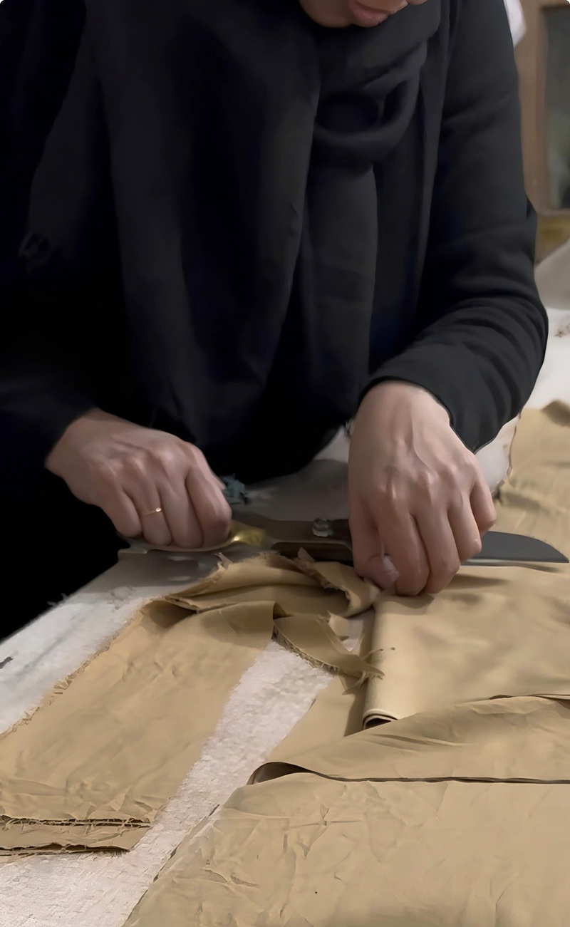 Hands cutting cotton fabric with scissors