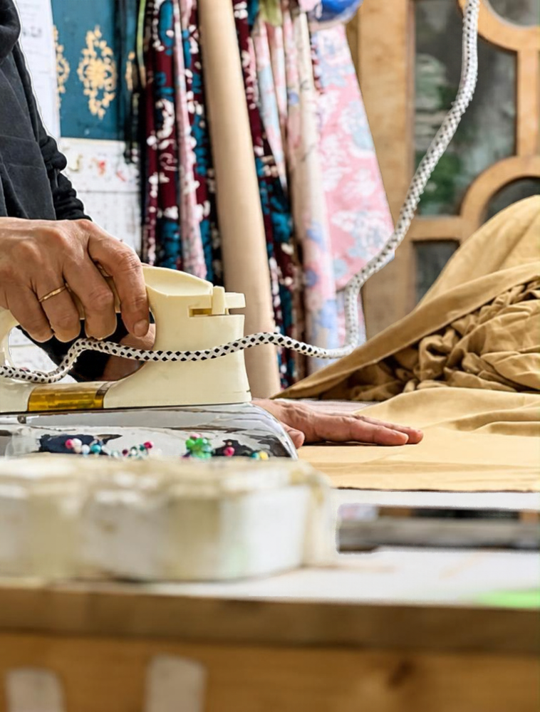Hands ironing fabric in the atelier