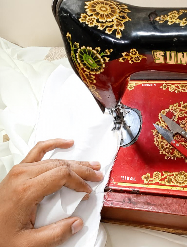 Hands guiding fabric through a sewing machine